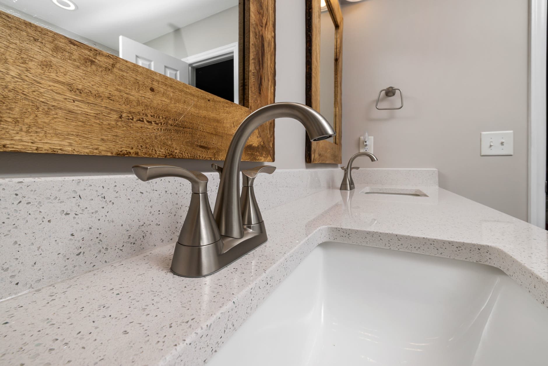 Brushed-nickel lavatory faucet on a white vanity, the kind of fixture that blows a plumbing allowance if nobody writes the actual down