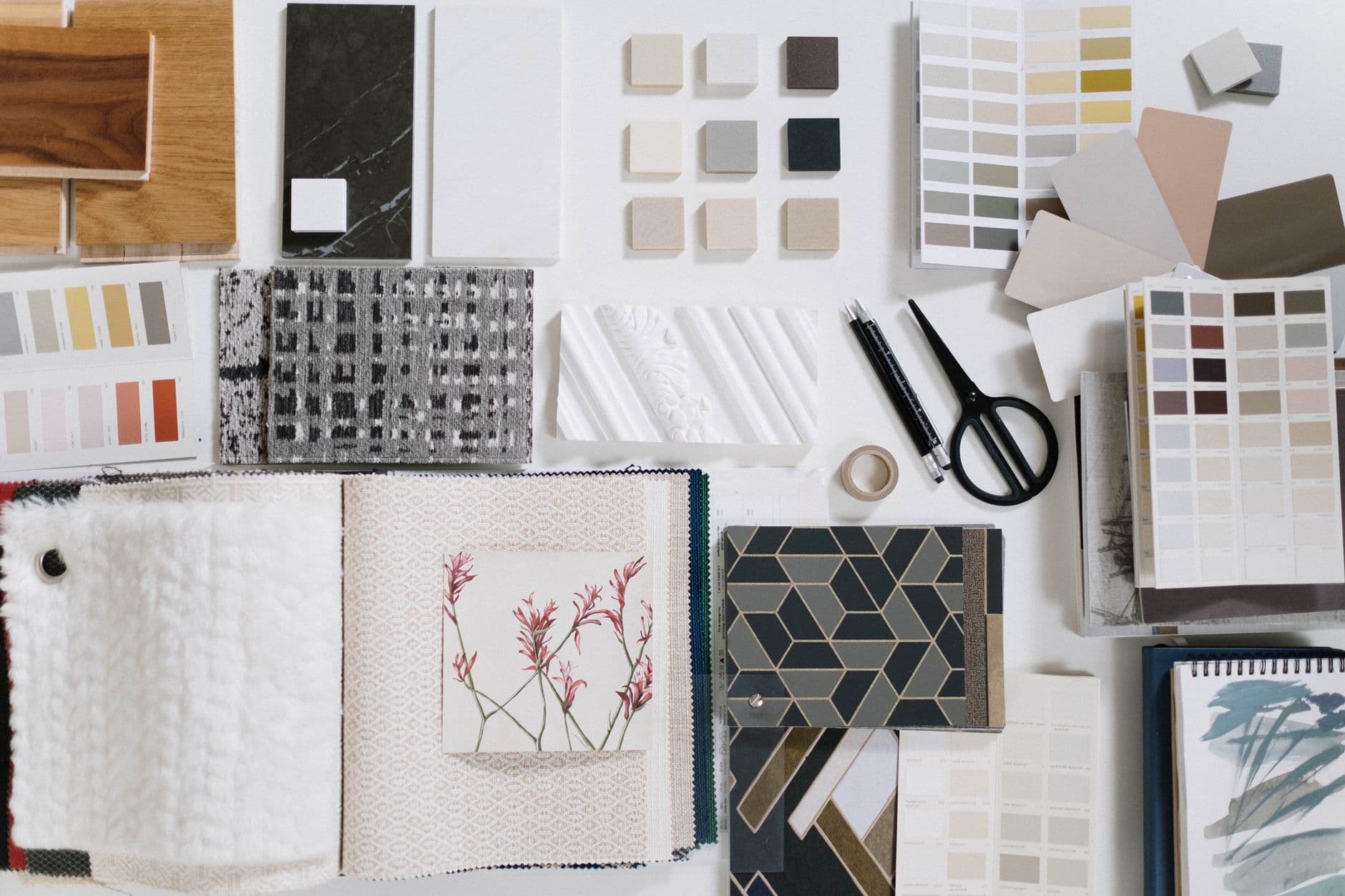Tile, paint and fabric finish samples laid out in rows on a work surface